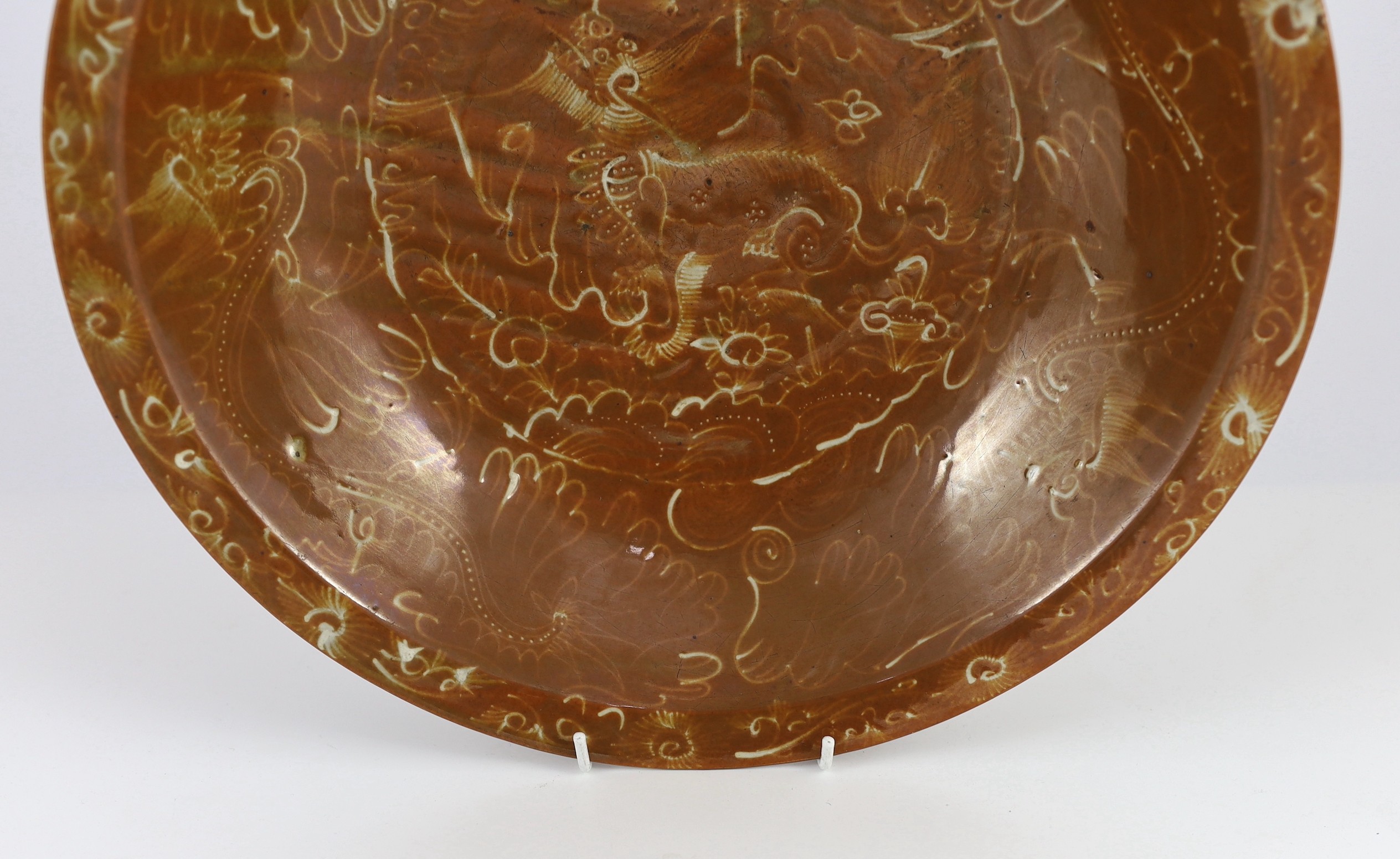 A Chinese Swatow slip-decorated brown ground dish, Zhangzhou kilns, early 17th century, 37cm diameter